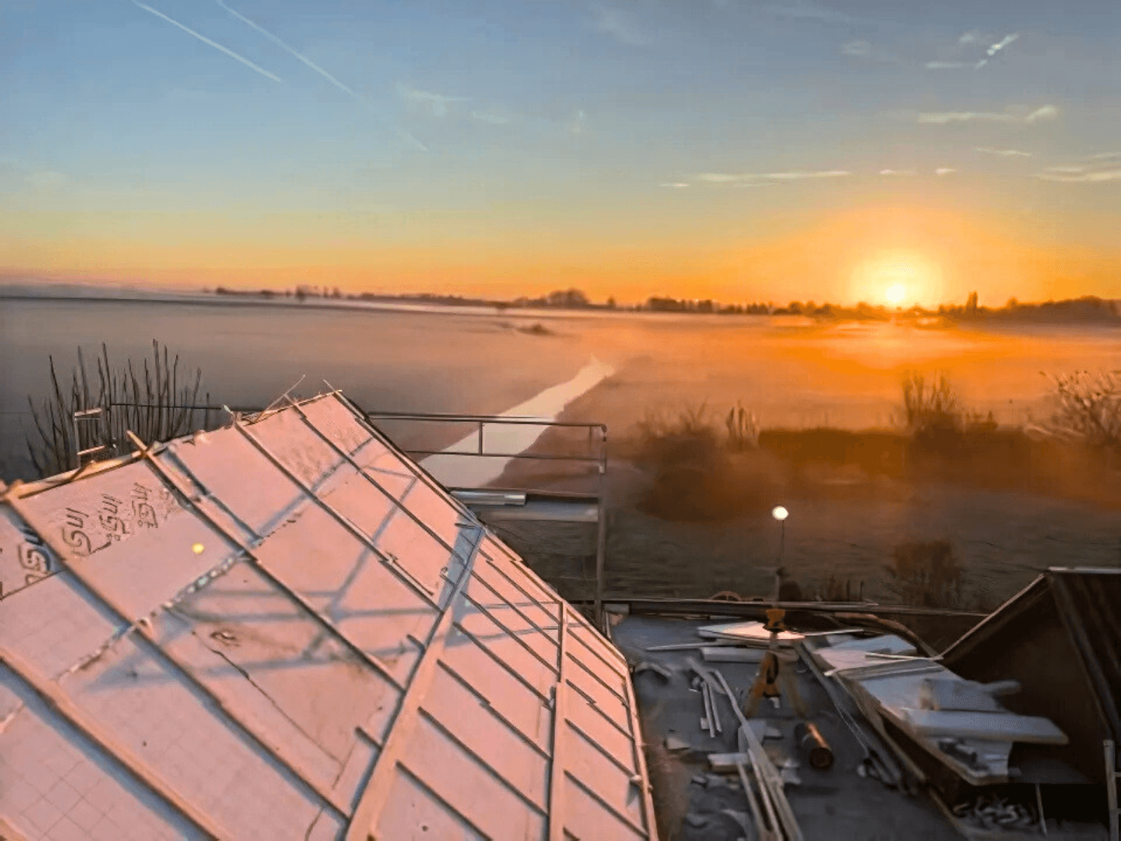 Zonsopkomst boven het geïsoleerde dakvlak tijdens de dakrenovatie in Meeuwen